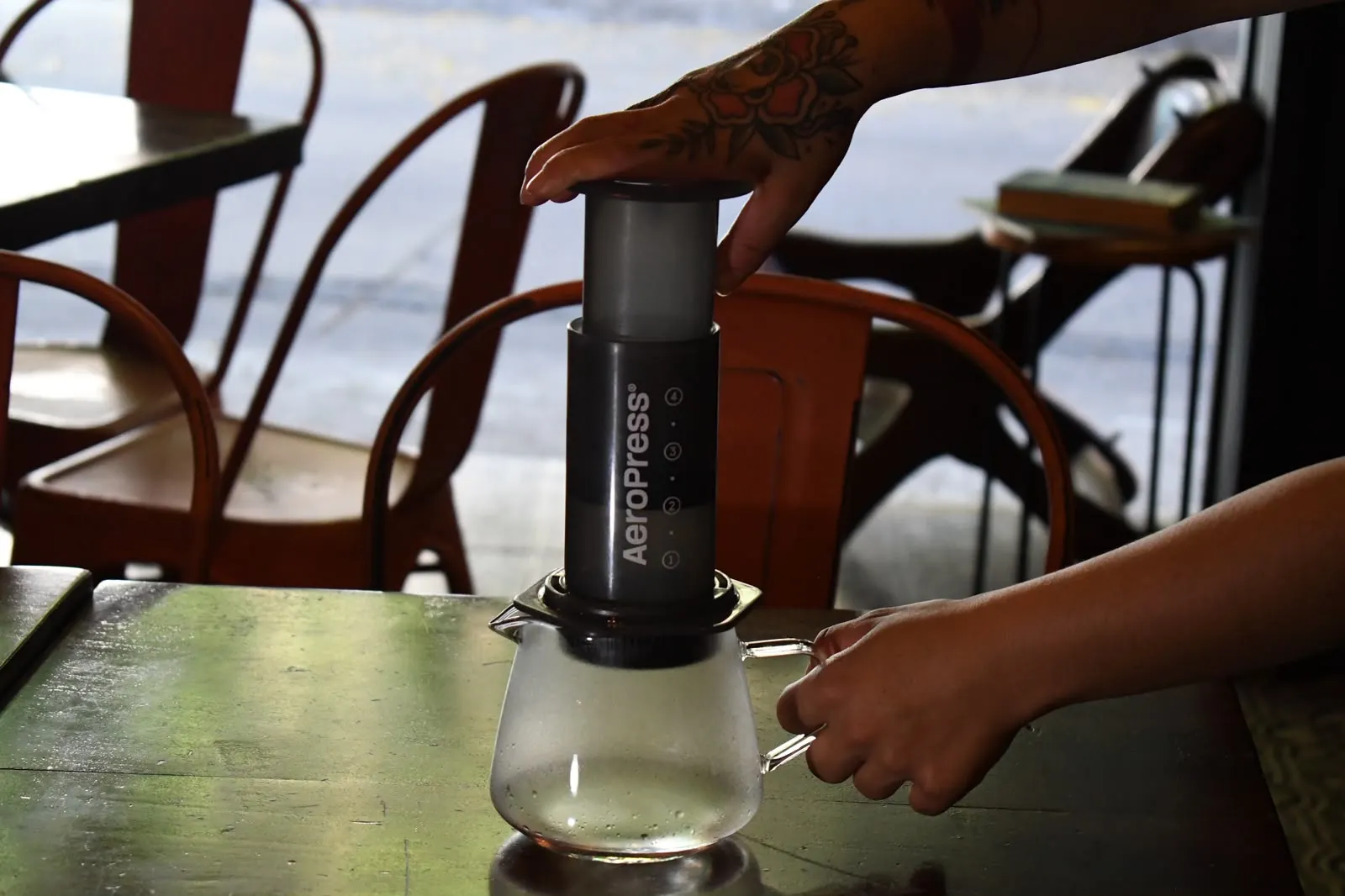 AeroPress montada sobre una jarra de cristal en una mesa de la terraza de Monono Coffee