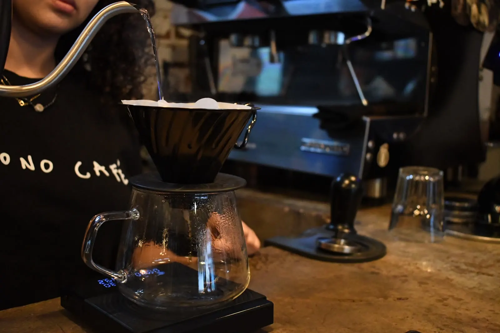 Barista de Monono Coffee vertiendo agua en un dripper V60 sobre la barra